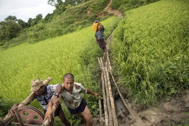 Men carry a machine as a man walks behind them with a container of crude oil at Yaynan Taung (Oil Mountain) in Kyaukpyu township, Rakhine state, Myanmar October 6, 2015. (Photo by Soe Zeya Tun/Reuters)