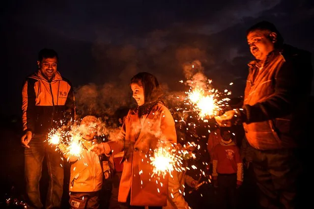 Hindu devotees light sparklers before worshipping the rising sun during the Chhath Festival, at the Bagmati River in Kathmandu on November 21, 2020. (Photo by Prakash Mathema/AFP Photo)