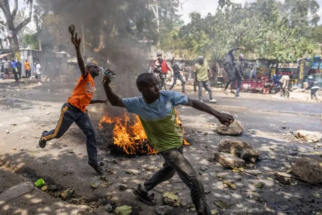 Protesters throw rocks towards police in the Kibera slum of Nairobi, Kenya Monday, March 20, 2023. (Photo by Ben Curtis/AP Photo)