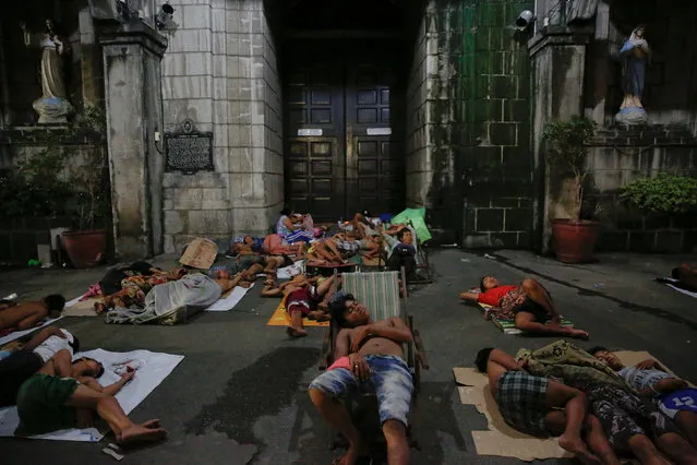 People sleep outside a church in Manila, Philippines early October 18, 2016. People who have been spending their nights outside the church for a long time, say there are more people joining them since the beginning of the country's war on drugs. (Photo by Damir Sagolj/Reuters)