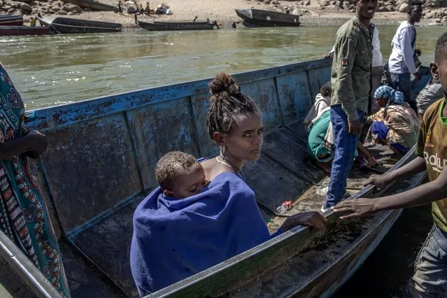 A woman who fled the conflict in the Ethiopia's Tigray waits to go back to Ethiopia with her baby on the banks of the Tekeze River on the Sudan-Ethiopia border, in Hamdayet, eastern Sudan, Tuesday, December 1, 2020. (Photo by Nariman El-Mofty/AP Photo)