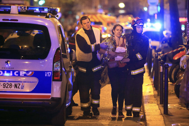 Rescue workers help a woman after a shooting, outside the Bataclan theater in Paris, November 13, 2015. (Photo by Thibault Camus/AP Photo)