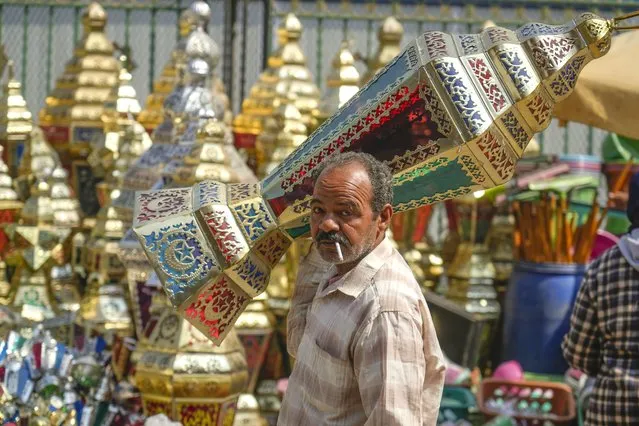 A man carries a traditional lantern in Sayyeda Zeinab market ahead of the upcoming Muslim fasting month of Ramadan, in Cairo, Egypt, Tuesday, March 21, 2023.  (Photo by Amr Nabil/AP Photo)