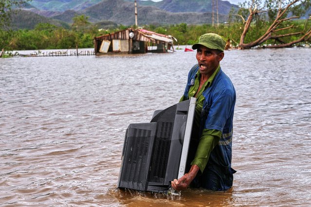 A man carries a TV from his home flooded by Hurricane Melissa in Santiago de Cuba, Wednesday, October 29, 2025. (Photo by Ramon Espinosa/AP Photo)