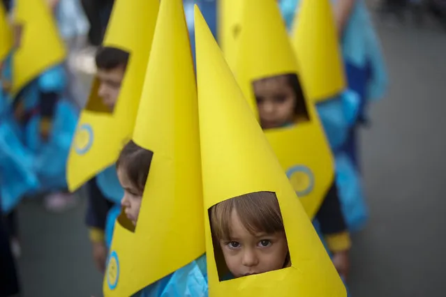 Children wearing hoods as penitents take part in a procession during the eve of Holy Week at Salesians school in Cordoba, southern Spain, Friday, March 31, 2023. Hundreds of processions will take place throughout Spain during the Easter Holy Week. (Photo by Manu Fernandez/AP Photo)