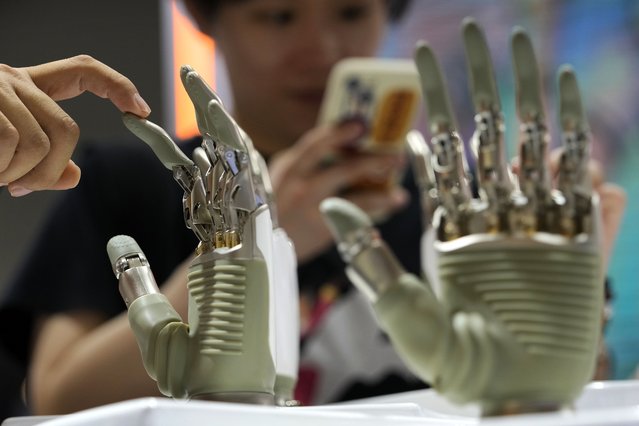A visitor touches a humanoid robot hand on display at an AI exhibition booth during the The World Artificial Intelligence Conference & High-Level Meeting on Global AI Governance, in Shanghai China, July 4, 2024. (Photo by Andy Wong/AP Photo)