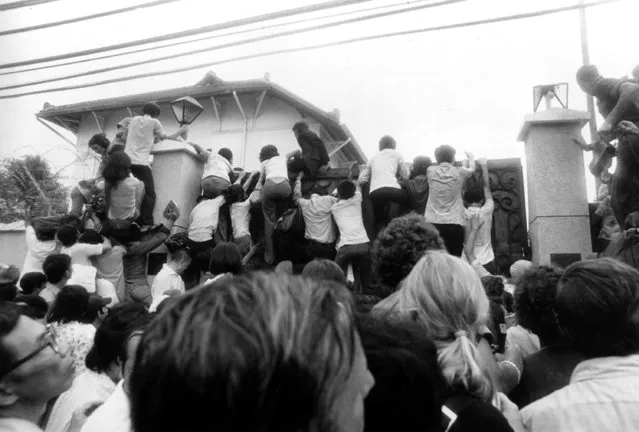 South Vietnamese civilians try to scale the high U.S. Embassy wall in desperate attempts to get abroad on the evacuation flights in Saigon, Vietnam, April 30, 1975.  (Photo by Neal Ulevich/AP Photo)