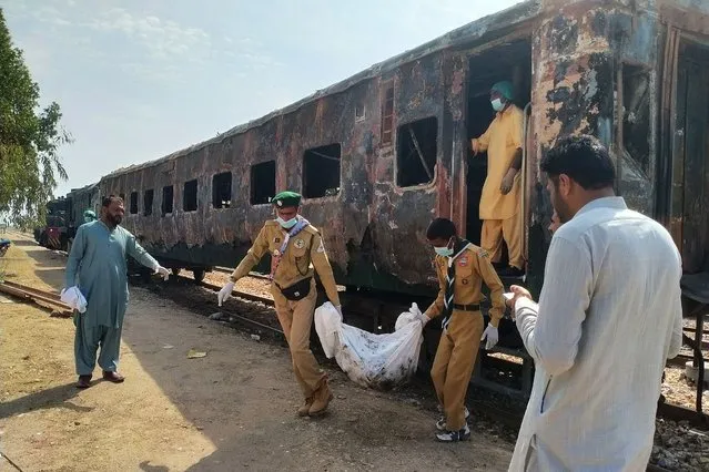 Scouts move the remains of a victim following an overnight fire in a carriage of the Karachi Express passenger train near Sukkur, some 450 km north of the port city of Karachi on April 27, 2023. At least seven people, including five of a family, died when a vagon of a passanger train caught fire in southern Pakistan overnight, an offical on April 27 said. (Photo by Shahid Ali/AFP Photo)