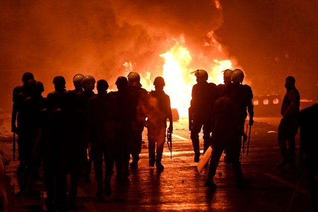 Pakistani policemen gather in front of a burning road tax collection point after it was set on fire by angry activists of the Tehreek-e-Labbaik Pakistan (TLP) party, in Lahore on October 10, 2025, ahead of their pro-Palestinian march towards Islamabad. (Photo by Arif Ali/AFP Photo)