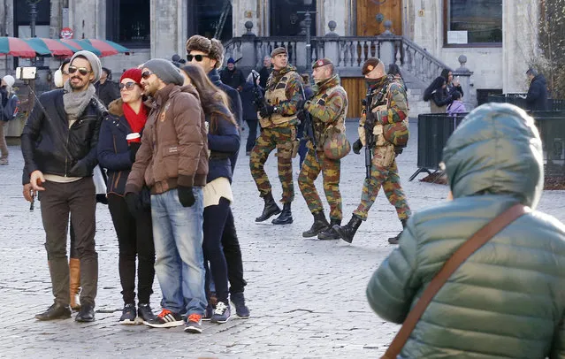 Tourists take a selfie as three Belgium army soldiers pass by on the Grand Place in Brussels, Belgium, Saturday, November 28, 2015. Brussels lowered its terror alert from level  four to three. (Photo by Michael Probst/AP Photo)