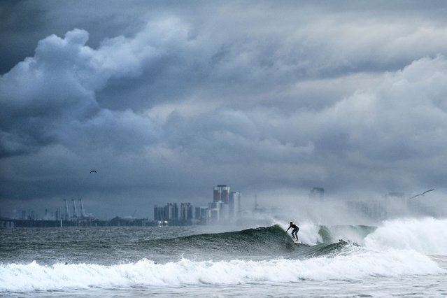 A surfer rides a wave as clouds gather above Bolsa Chica State Beach in Orange County, Calif., on Saturday, November 15, 2025. (Photo by Noah Berger/AP Photo)