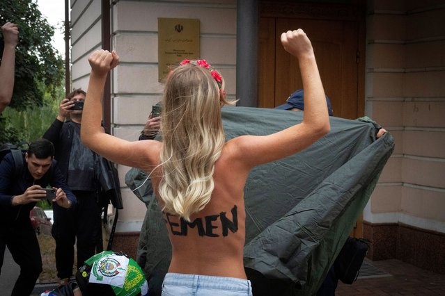 A police officer covers a topless activist of the Femen feminist group protesting in front of the Iranian Embassy in Kyiv, Ukraine, Friday, October 4, 2024. (Photo by Efrem Lukatsky/AP Photo)