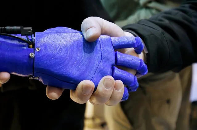 A man shakes hands with a robotic prosthetic hand in the Intel booth at the International Consumer Electronics show (CES) in Las Vegas, Nevada January 6, 2015. (Photo by Rick Wilking/Reuters)
