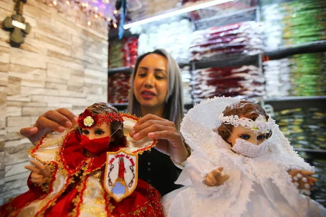 A saleswoman adjusts the suit of a dressed-up doll representing baby Jesus wearing a face mask to promote the use of masks, as a precautionary measure amid the coronavirus disease (COVID-19) outbreak before Christmas celebration, inside a store in Mexico City, Mexico, December 9, 2020. (Photo by Edgard Garrido/Reuters)