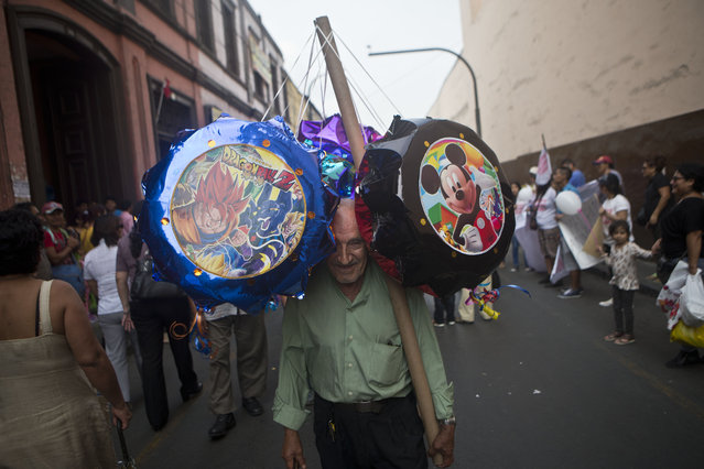 A street vendor walks around the central market selling pinatas that resemble balloons in Lima, Peru, Thursday, January 29, 2015. Each pinata, empty of treats inside, costs 20 soles, about $6.50 dollars. (Photo by Esteban Felix/AP Photo)