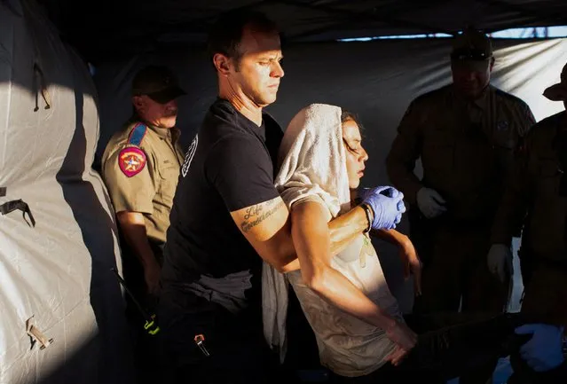Firefighter EMT William Dorsey lifts a migrant woman suffering from heat exhaustion onto a stretcher in the border community of Eagle Pass, Texas, U.S. June 26, 2023. (Photo by Kaylee Greenlee Beal/Reuters)