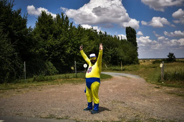 A dressed-up spectator waves from the side of the road as he waits to watch riders during the first stage of the 105th edition of the Tour de France cycling race between Noirmoutier-en-l'ile and Fontenay-le Comte, western France, on July 7, 2018. (Photo by Marco Bertorello/AFP Photo)