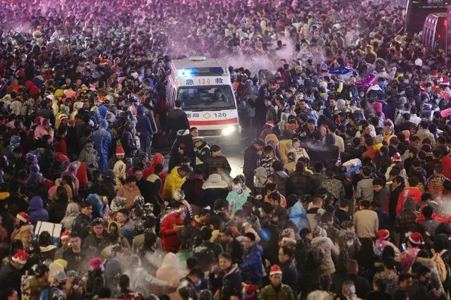 An ambulance is seen as people spray artificial snow during Christmas eve celebrations in Hengyang, Hunan province, December 24, 2015. (Photo by Reuters/China Daily)