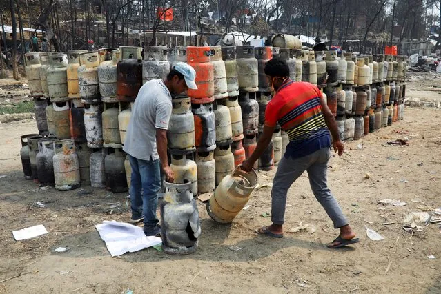 Men collect damaged liquefied petroleum gas (LPG) cylinders at a refugee camp after a massive fire broke out two days ago and destroyed thousands of shelters in Cox's Bazar, Bangladesh, March 24, 2021. (Photo by Mohammad Ponir Hossain/Reuters)