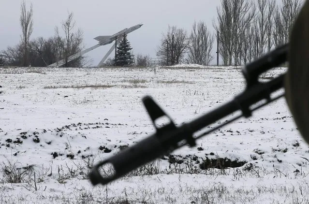 A weapon of a pro-Russian separatist is pictured as a monument with a Soviet MiG-21 jet fighter is seen in the distance on the outskirts of Vuhlehirsk, eastern Ukraine February 10, 2015. (Photo by Maxim Shemetov/Reuters)