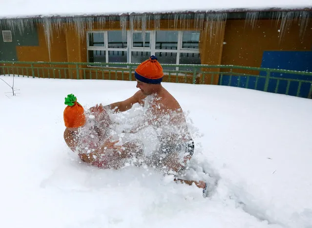 Members of a local winter swimmers club play in the snow after pouring buckets of cold water over themselves during a celebration of Polar Bear Day at the Royev Ruchey zoo, with the air temperature at about minus 5 degrees Celsius (23 degrees Fahrenheit), in Krasnoyarsk, Russia, November 27, 2016. (Photo by Ilya Naymushin/Reuters)