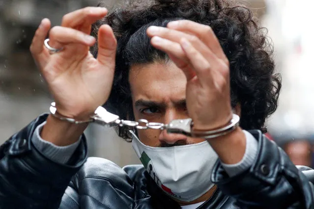 A person holds up his handcuffed hands as part of a protest of restaurant and small business owners who call for their businesses to be allowed to re-open, despite no authorization for the demonstration by the government, amid the coronavirus disease (COVID-19) outbreak, in Rome, Italy, April 12, 2021. (Photo by Guglielmo Mangiapane/Reuters)
