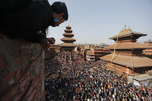 People watch devotees pulling a chariot in Biska Jatra Festival in Bhaktapur, Nepal, Saturday, April 10, 2021. During this festival, also regarded as Nepalese New Year, images of Hindu god Bhairava and his female counterpart Bhadrakali are enshrined in two large chariots and pulled to an open square after which rituals and festivities are performed. (Photo by Niranjan Shrestha/AP Photo)