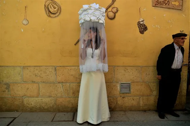 One of the “Las Doncellas” (maidens), holds a basket covered with white cloth transporting a loaf of bread on her head, during the “Bread Procession of the Saint”, the ceremony in honor of Saint Domingo de La Calzada (1019-1109) who helped poor people and pilgrimage, in Santo Domingo de La Calzada, northern Spain, Wednesday May 11, 2022. It has been 2 years since the last proceesion due to COVID-19 restrictions. (Photo by Alvaro Barrientos/AP Photo)