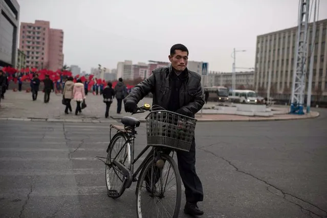 A pedestrian pushes a bicycle across a street in Pyongyang on November 26, 2016. (Photo by Ed Jones/AFP Photo)