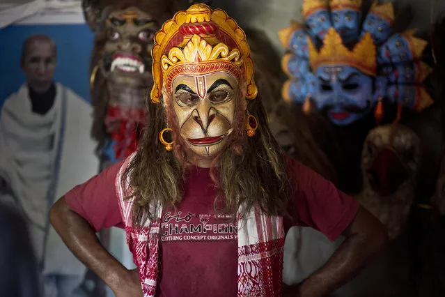 In this Tuesday, August 7, 2018 photo, mask maker Khagen Goswami wears a mask of Hindu monkey god Hanuman at Samaguri Satra, a Vaishnavite monastery, in Majuli, India. Vaishnavite practice is credited with preserving the culture of mask-making, an integral part of the dance dramas or Bhaonas. At the Samaguri Satra, the monks use locally available bamboo, cane, clay, paper, jute and cow dung to shape and paint masks depicting characters from Hindu mythology. (Photo by Anupam Nath/AP Photo)