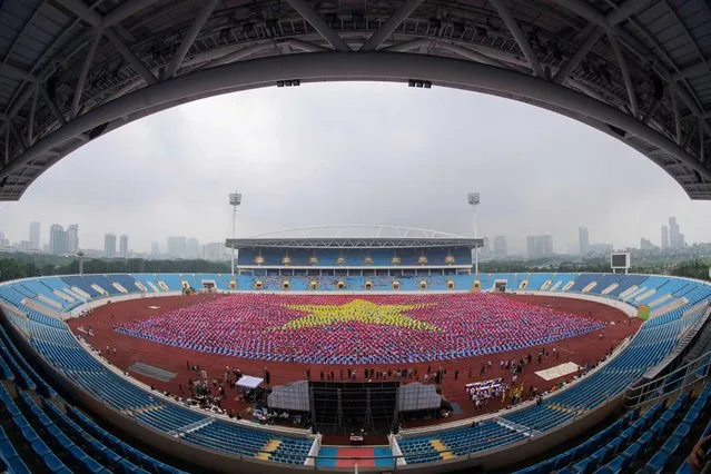 Participants hold up coloured cloths to form the Vietnamese flag during a mass yoga event in My Dinh National Stadium in Hanoi on August 12, 2023 (Photo by Tien Tuan/AFP Photo)