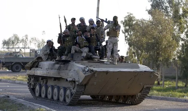 Iraqi security forces and Shi'ite fighters pose on a tank in the Salahuddin province March 2, 2015. Iraq's armed forces, backed by Shi'ite militia, attacked Islamic State strongholds north of Baghdad on Monday as they launched an offensive to retake the city of Tikrit and the surrounding Sunni Muslim province of Salahuddin.     REUTERS/Thaier Al-Sudani (IRAQ - Tags: POLITICS CONFLICT CIVIL UNREST)