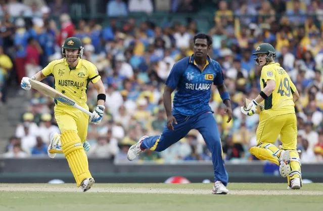 Captains Michael Clarke (L) of Australia and Angelo Mathews (C) of Sri Lanka watch a shot from Clarke as it heads for the boundary during their Cricket World Cup match in Sydney, March 8, 2015.    REUTERS/Jason Reed (AUSTRALIA - Tags: SPORT CRICKET)