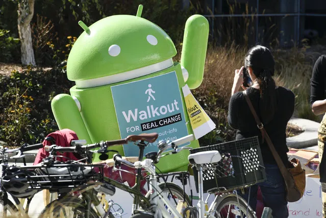 A person takes a photograph of an Android statue displaying a sign that reads “Walkout For Real Change” during a protest outside Google headquarters in Mountain View, California, U.S., on Thursday, November 1, 2018. Hundreds of employees gathered in the campus' main quad to rally against sexual harassment. (Photo by Michael Short/Bloomberg via Getty Images)