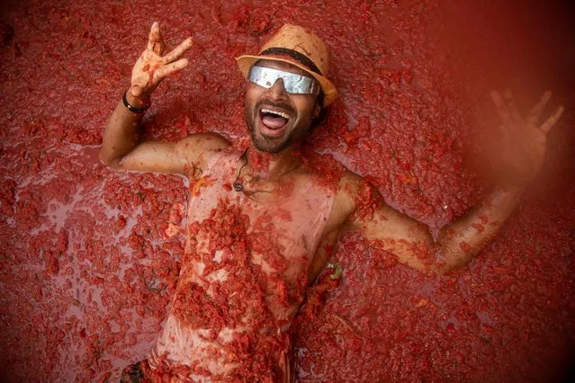 A reveller lies on a street flooded with tomato pulp during the “Tomatina” annual food-battle in the Spanish eastern town of Bunol, on August 30, 2023. Around 15,000 people, gathered today in Spain's annual “Tomatina” street battle to hurl each other 120 tons of tomatoes. (Photo by Jose Miguel Fernandez/AFP Photo)