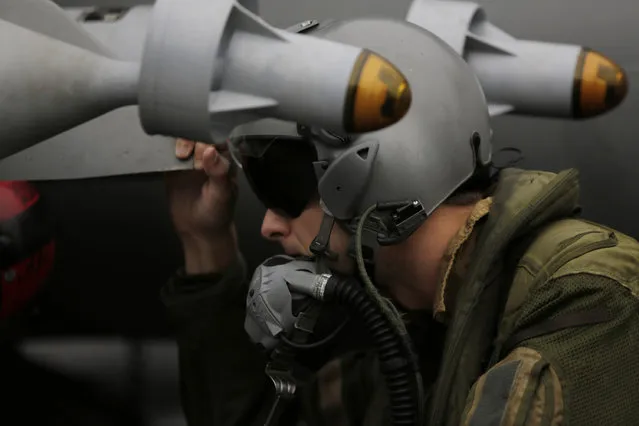 In this Wednesday, March 18, 2015 photo, a French pilot checks the bombs on his  military plane before taking off from the flight deck of the French Navy aircraft carrier Charles de Gaulle in the Persian Gulf. (Photo by Hasan Jamali/AP Photo)