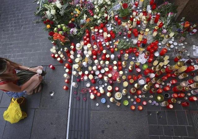 A young woman lights a candle in front of a closed and cordoned off department store in the city centre of Wuerzburg, Germany, Saturday, June 26, 2021. Authorities say a man armed with a long knife killed several people and injured others, some seriously, in Germany’s southern city of Wuerzburg on Friday before being shot by police and arrested. (Photo by Karl-Josef Hildenbrand/dpa via AP Photo)