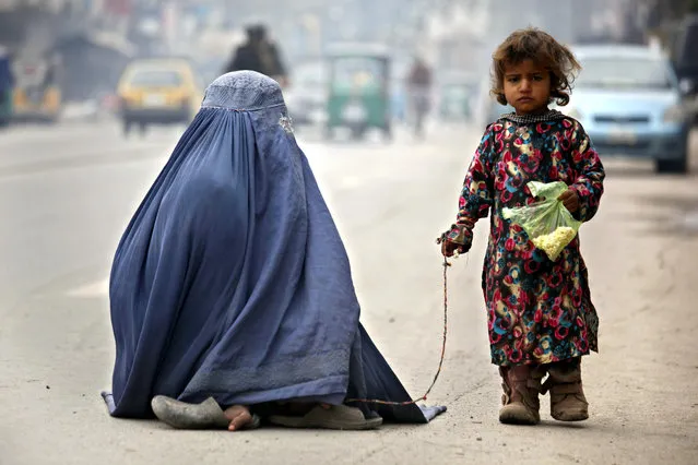 A burqa-clad mother and her daughter begs for alms on a road in Peshawar, Pakistan, 08 May 2016. Mother's day is celebrated on second Sunday of  May in a large number of countries to honour mothers and for appreciation of motherhood. (Photo by Arshad Arbab/EPA)