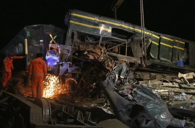Railway workers try to clear the track at the site of a train collision in the Ghotki district, southern Pakistan, late Monday, June 7, 2021. An express train barreled into another that had derailed in Pakistan before dawn Monday, killing dozens of passengers, authorities said. More than 100 were injured, and rescuers and villagers worked throughout the day to search crumpled cars for survivors and the dead. (Photo by Fareed Khan/AP Photo)
