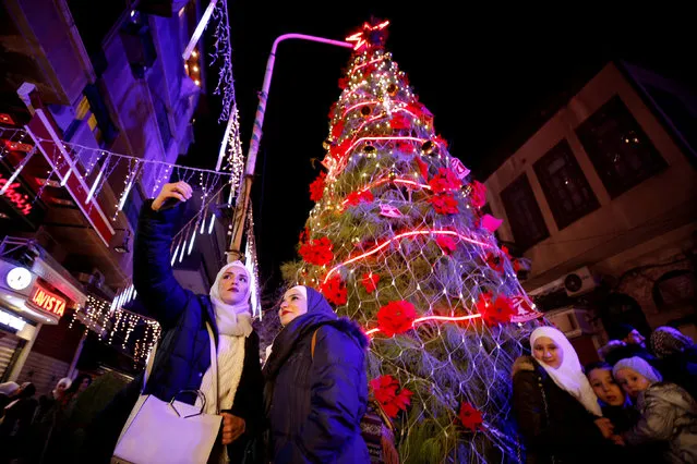 People take a selfie in front of a Christmas tree in the Qasaa district, Damascus, Syria December 14, 2018. (Photo by Omar Sanadiki/Reuters)