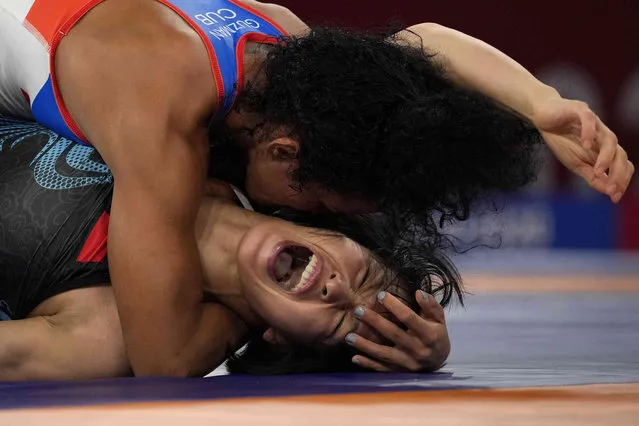 China's Sun Yanan, bottom, reacts as she competes against Cuba's Yusneylis Guzman Lopez during their women's freestyle 50kg wrestling match at the 2020 Summer Olympics, Friday, August 6, 2021, in Chiba, Japan. (Photo by Aaron Favila/AP Photo)