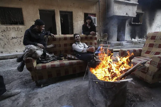 “Free Syrian Army” fighters sit around a fire along a street in Deir al-Zor, eastern Syria December 6, 2013. (Photo by Khalil Ashawi/Reuters)