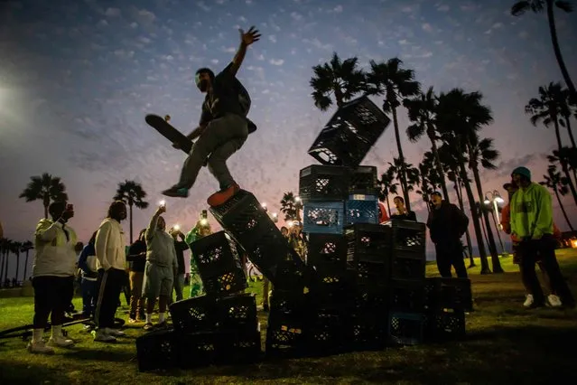 A man falls down of a pyramid of milk crates while he participates of the Milk Crate Challenge, on August 24, 2021 in Venice, California. The Milk Crate Challenge, where participants walk up a pyramid of milk crates has gone viral in recent days on social media. According to US media some doctors are also warning that the injuries from the challenge are putting more stress on hospitals at a time when emergency rooms nationwide are overwhelmed because of the surge in coronavirus. (Photo by Apu Gomes/AFP Photo)