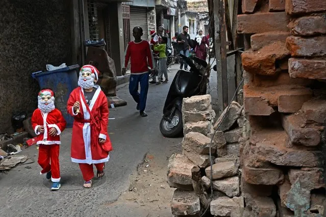 In this photograph taken on December 19, 2023, children dressed as Santa Claus walk along a street, ahead of Christmas festivities in Kolkata. (Photo by Dibyangshu Sarkar/AFP Photo)