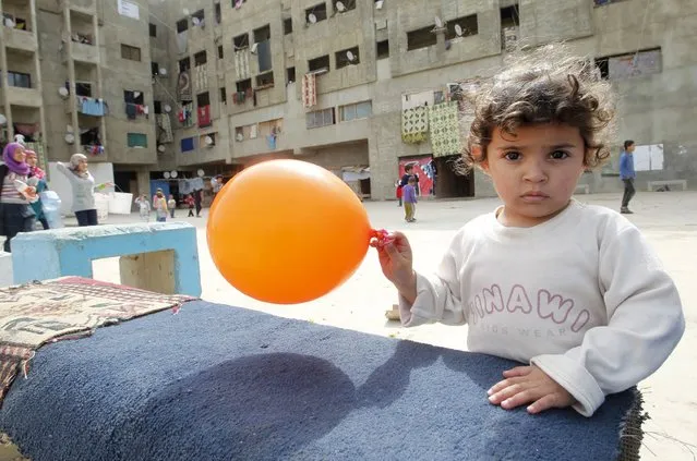 A child plays with a balloon inside a compound for Syrian Refugees in Sidon, south Lebanon April 17, 2015. (Photo by Ali Hashisho/Reuters)