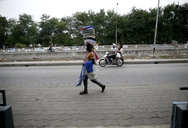 A man carries cloths on his head as he walks along a road in Cotonou, March 5, 2016. (Photo by Akintunde Akinleye/Reuters)