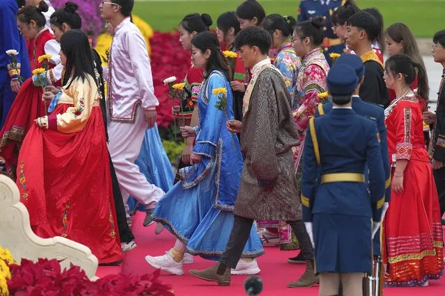 Attendees wearing traditional costumes walk with flowers as they head to pay respects to the People's Heroes Monument during a ceremony to mark Martyr's Day at Tiananmen Square in Beijing, Thursday, September 30, 2021. Chinese President Xi Jinping paid respects at a solemn commemoration Thursday for those who died in the struggle to establish Communist Party rule, as he leads a national drive to reinforce patriotism and single-party authority. (Photo by Andy Wong/AP Photo)