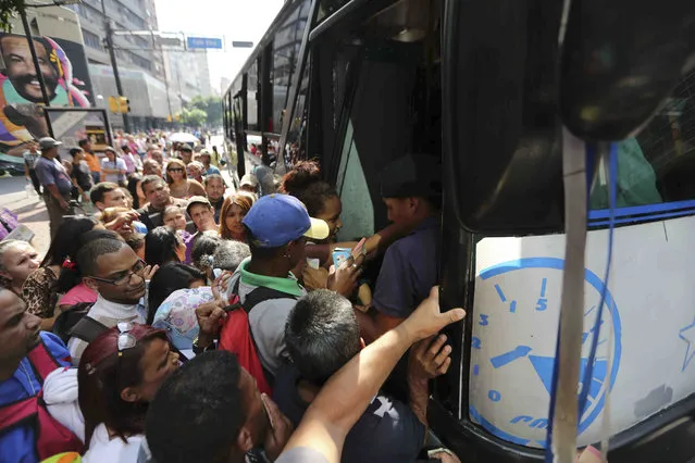 People jockey to enter a bus during a power outage that suspended the subway service in Caracas, Venezuela, Monday, March 25, 2019. (Photo by Fernando Llano/AP Photo)