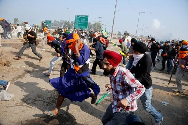 Farmers, who are marching towards New Delhi to press for better crop prices promised to them in 2021, run for cover amidst tear gas fired by police to disperse them at Shambhu barrier, a border crossing between Punjab and Haryana states, India on February 21, 2024. (Photo by Adnan Abidi/Reuters)