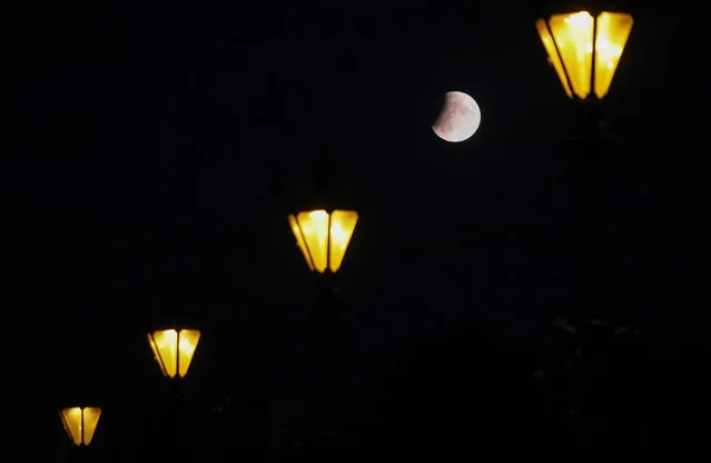 The partially hidden moon can be seen between street lamps in Berlin, Germany, 16 July 2019. The partial lunar eclipse on the night of 16 July 2019 will take place 50 years after the astronauts Neil Armstrong, Buzz Aldrin and Michael Collins launched aboard a Saturn V rocket toward the Moon on 16 July 1969. The year 2019 marks the 50th anniversary of the first moon landing on 20 July 1969. (Photo by Felipe Trueba/EPA/EFE)